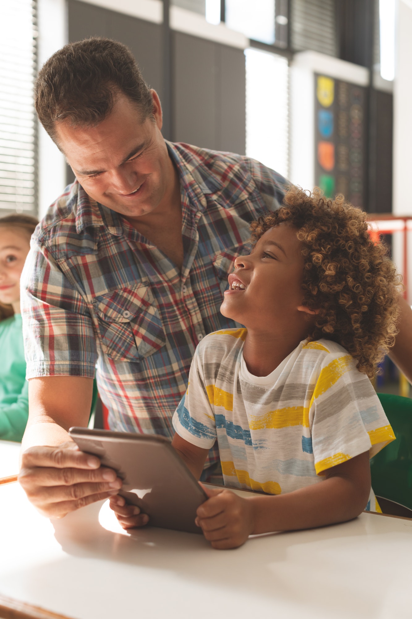 Teacher interacting with school boy over digital tablet in classroom at school